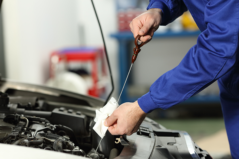 Technician replacing an oil filter and checking fluid levels in the service bay